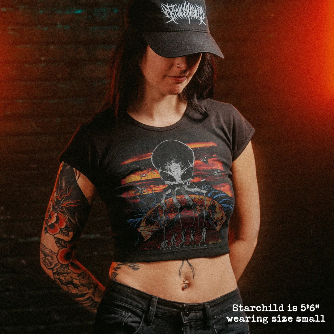 Female model wearing cropped baby tee with alien overlord graphic
