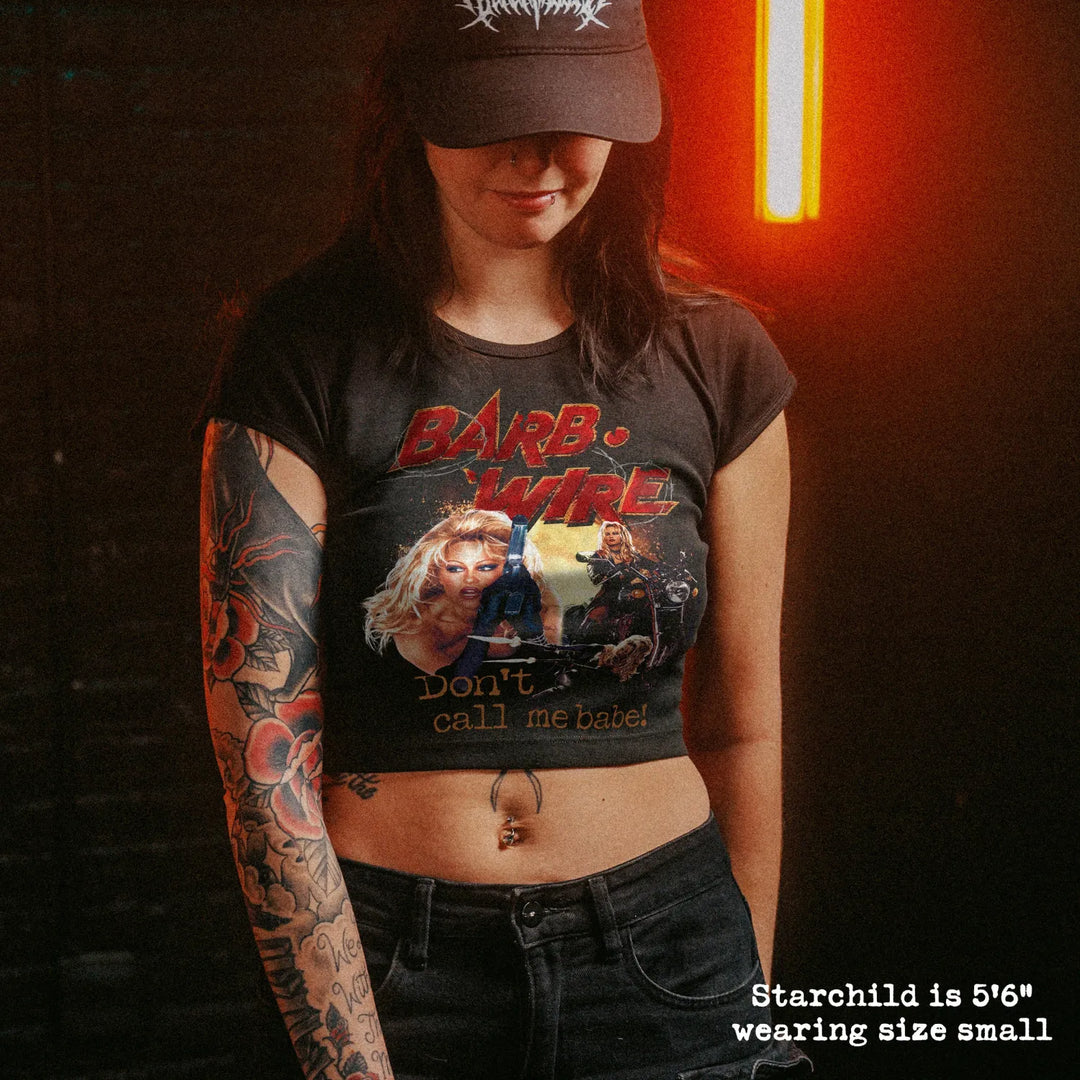 Female model wearing cropped baby tee with barb wire graphic

