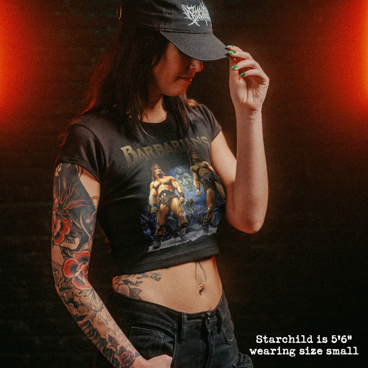 Female model wearing cropped baby tee with barbarians graphic
