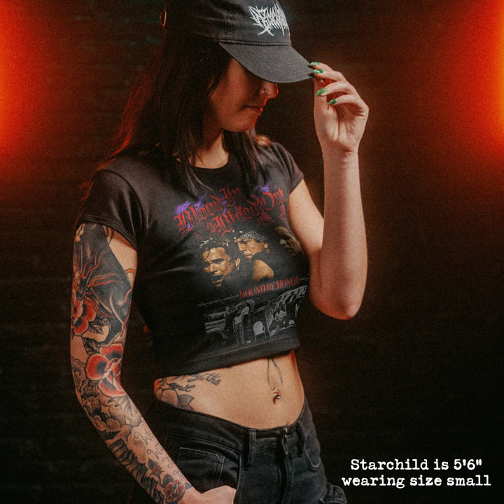 Female model wearing cropped baby tee with blood in blood out graphic
