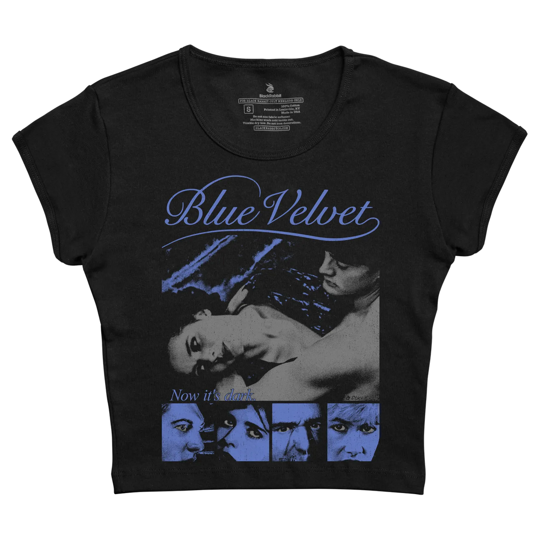 Black short-sleeved t-shirt featuring a blue-toned graphic of the ’blue velvet’ movie poster with the title in cursive script and the phrase “now it’s dark” below.