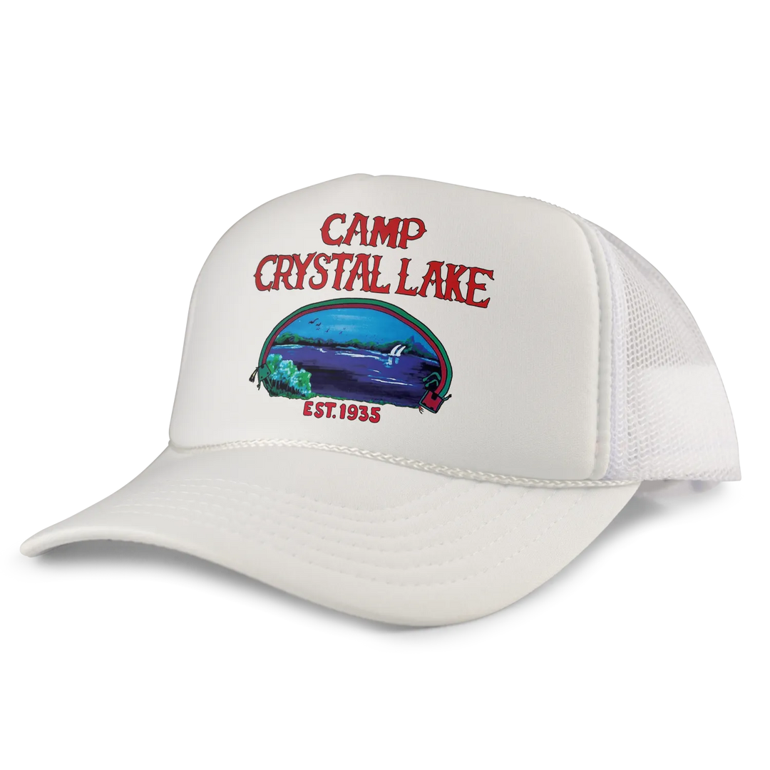 White trucker hat featuring a colorful ’camp crystal lake’ graphic with red lettering and an illustrated lake scene.