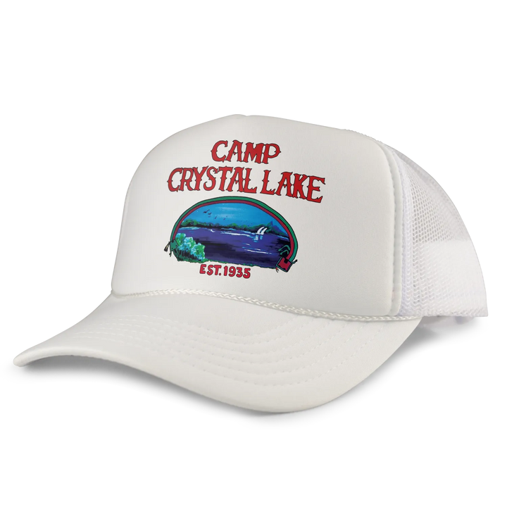 White trucker hat featuring a colorful ’camp crystal lake’ graphic with red lettering and an illustrated lake scene.