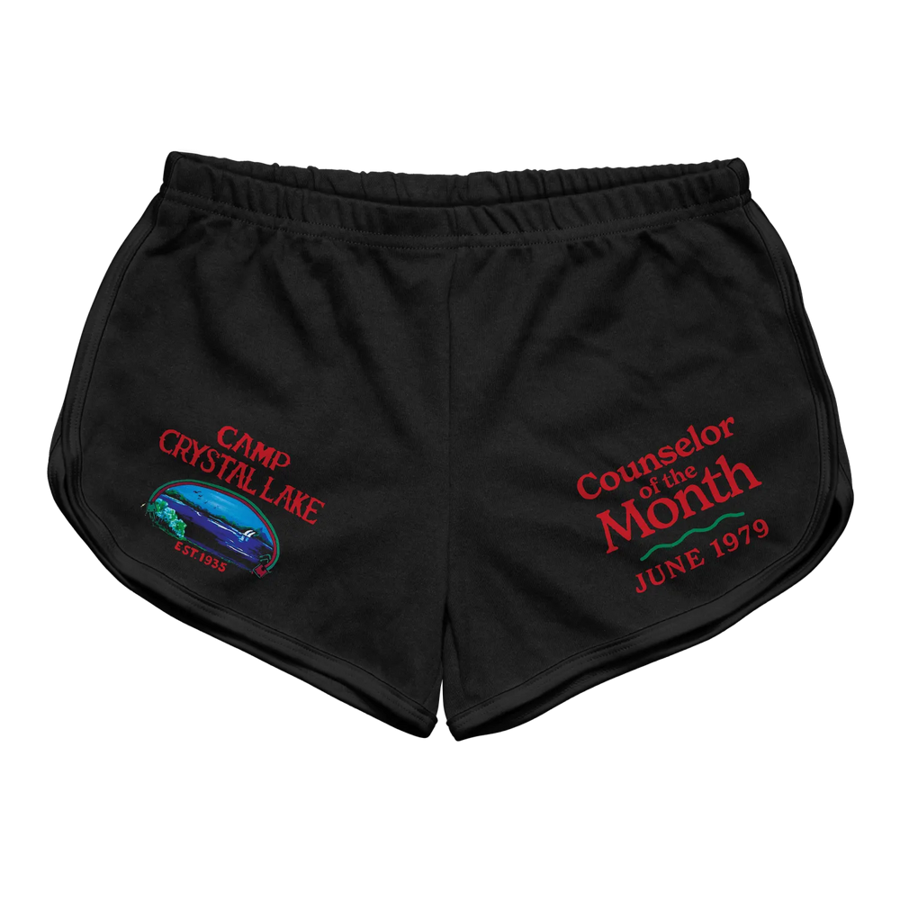 Black athletic shorts featuring embroidered red text and a colorful graphic of camp crystal lake with ’counselor of the month’ and ’june 1979.’