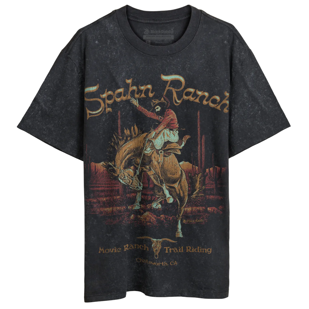 A dark gray, short-sleeved t-shirt with a vintage-style graphic of a cowboy riding a bucking horse in a desert landscape.