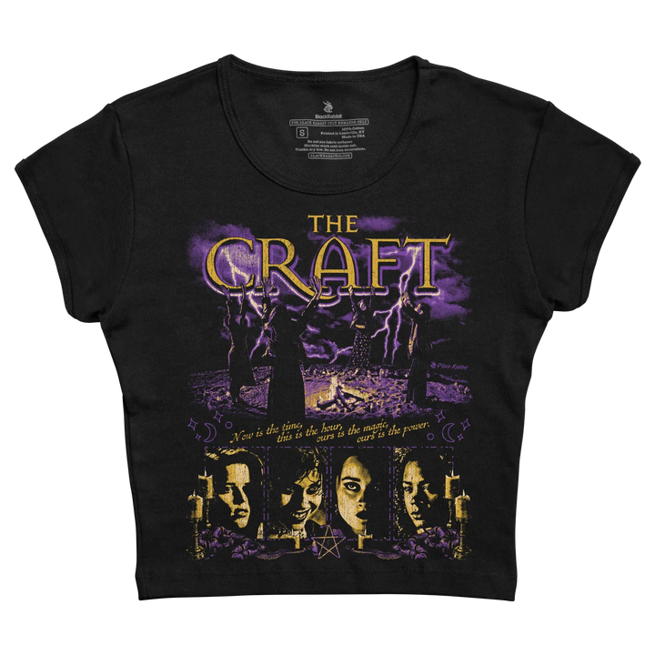 Black short-sleeved t-shirt featuring a purple and gold graphic of the movie ’the craft’ with silhouettes, lightning, candles, and faces beneath the title.