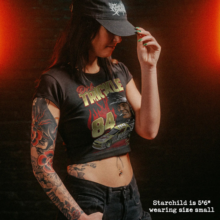 Female model wearing cropped baby tee with dick trickle graphic

