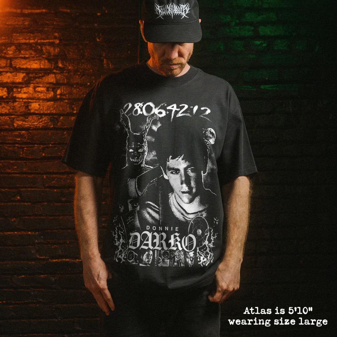Male model wearing heavy faded black tee with Donnie Darko graphic. 