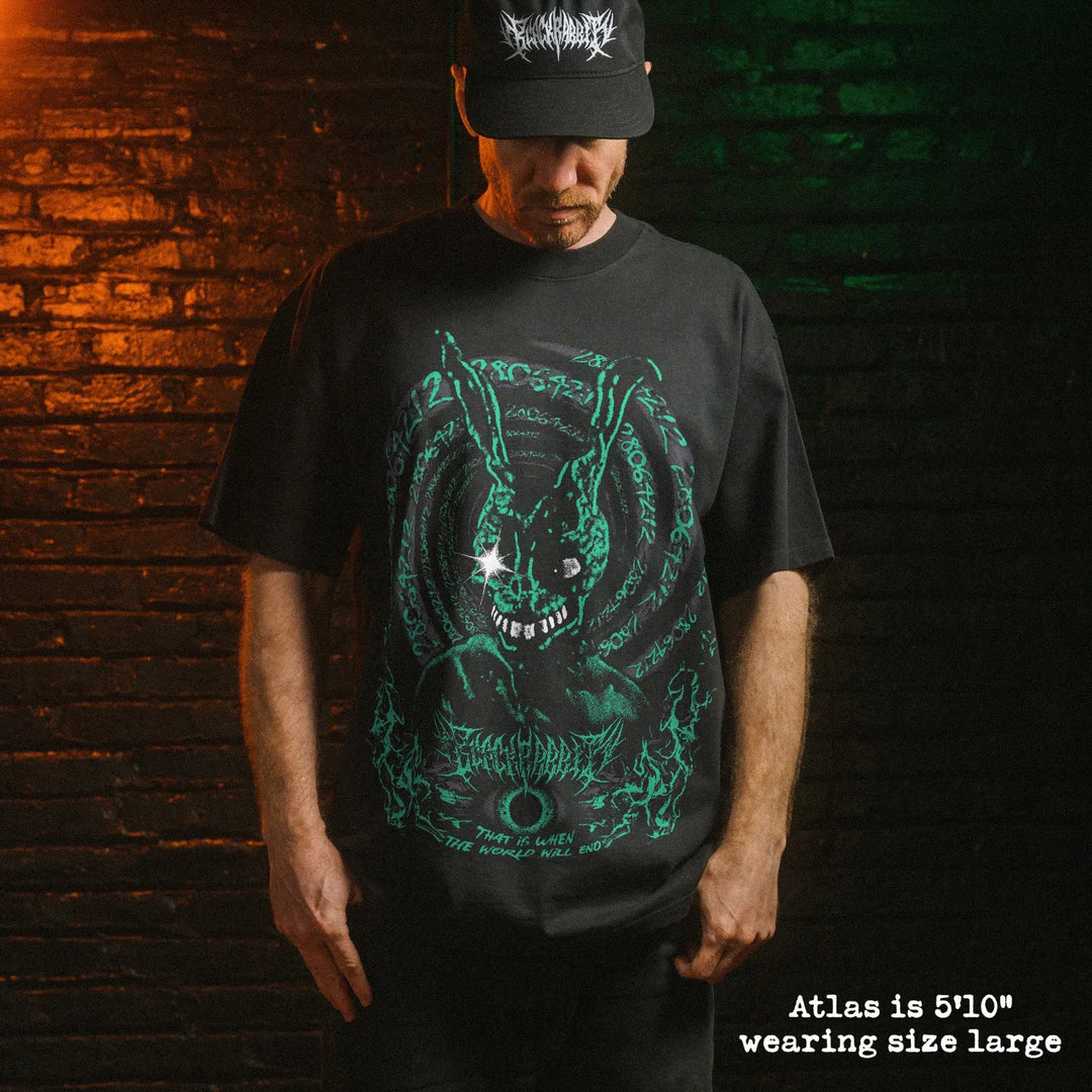 Male model wearing heavy faded black tee with Donnie Darko graphic. 