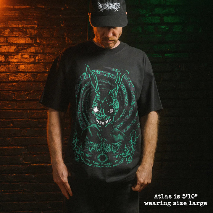 Male model wearing heavy faded black tee with Donnie Darko graphic. 