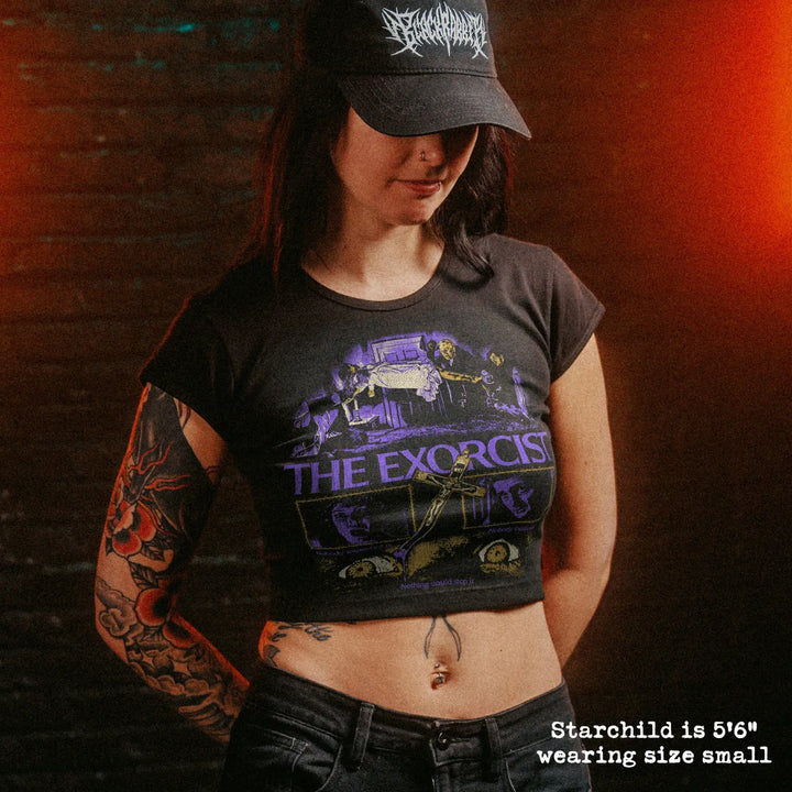 Female model wearing cropped baby tee with exorcist graphic
