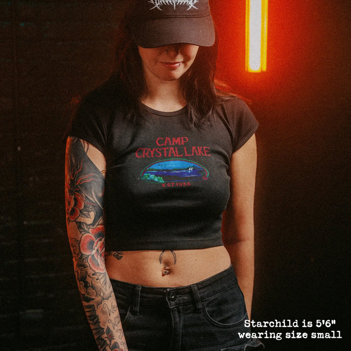 Female model wearing cropped baby tee with camp crystal lake graphic
