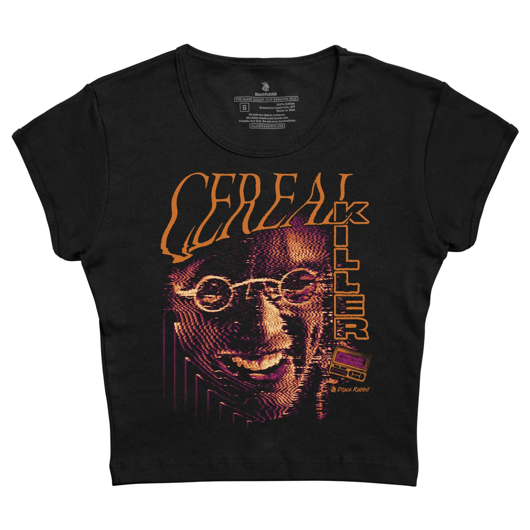 Black fitted cropped baby tee with Cereal Killer front graphic featuring a distorted face, orange lettering, purple accents, and retro horror styling. 