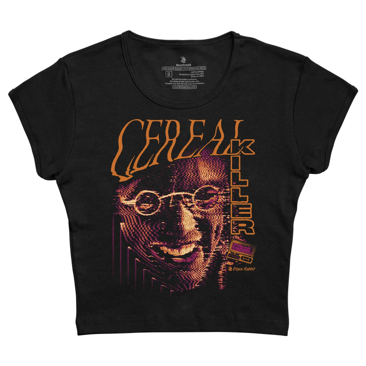 Black fitted cropped baby tee with Cereal Killer front graphic featuring a distorted face, orange lettering, purple accents, and retro horror styling. 
