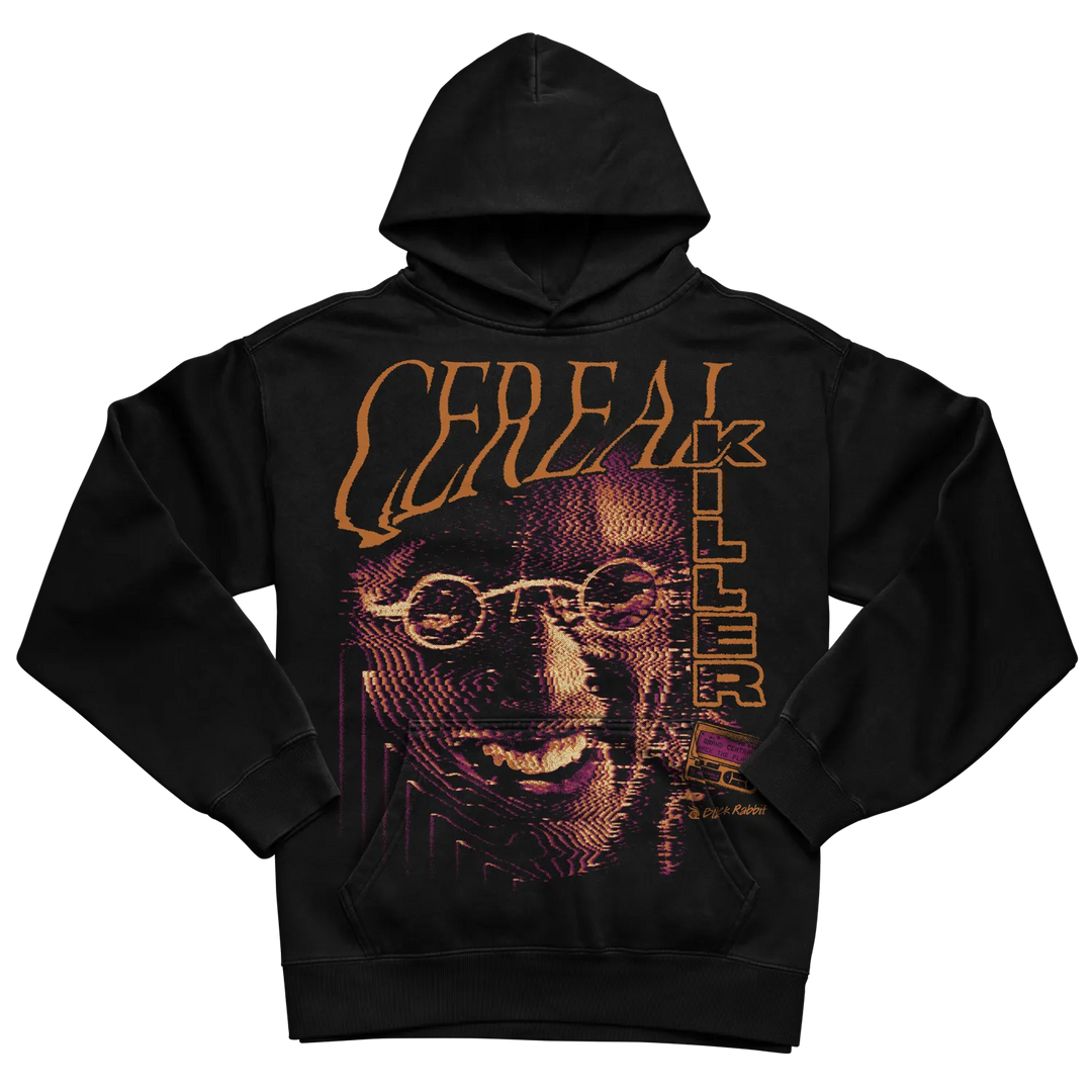Black pullover hoodie with oversized Cereal Killer graphic featuring a distorted face, orange lettering, and purple halftone details. 