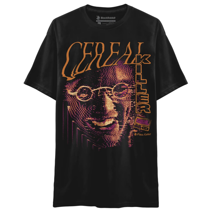 Black T-shirt with large Cereal Killer graphic featuring orange lettering, purple halftone face artwork, and retro horror-inspired design. 