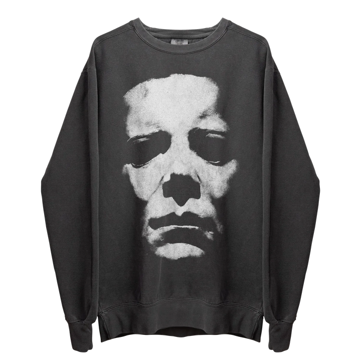 A dark gray crewneck sweatshirt with a large, distressed white graphic of a skull-like face on the front.