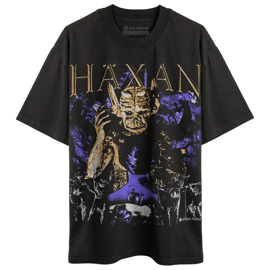 A black t-shirt with a graphic print featuring a demonic figure and the word ’HAXAN’ in gold lettering.