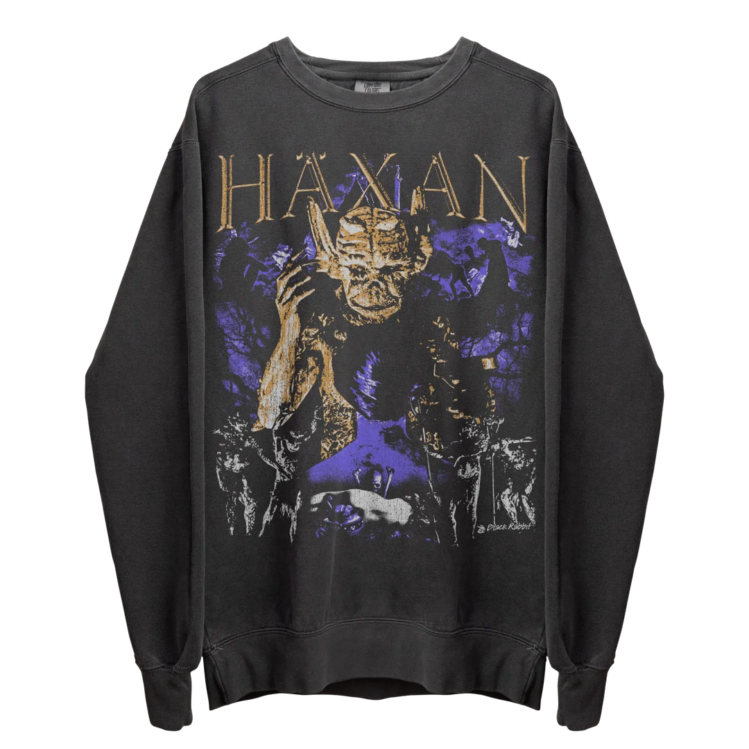 A dark gray long-sleeve sweatshirt with a ’Haxan’ graphic featuring a demon-like figure and purple and gold accents.