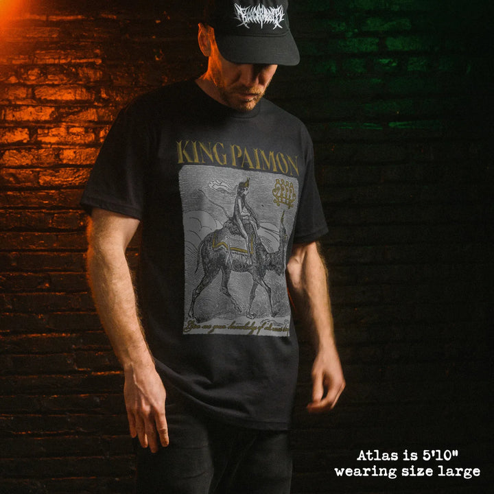 Black king paimon t-shirt with detailed gold and white figure riding donkey on preshrunk combed industry standard blank