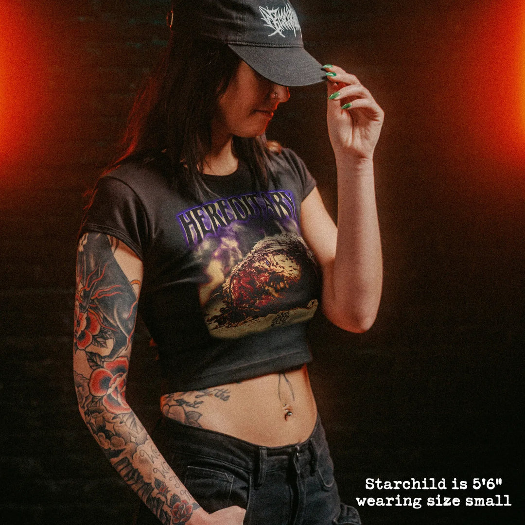 Female model wearing cropped baby tee with hereditary head graphic
