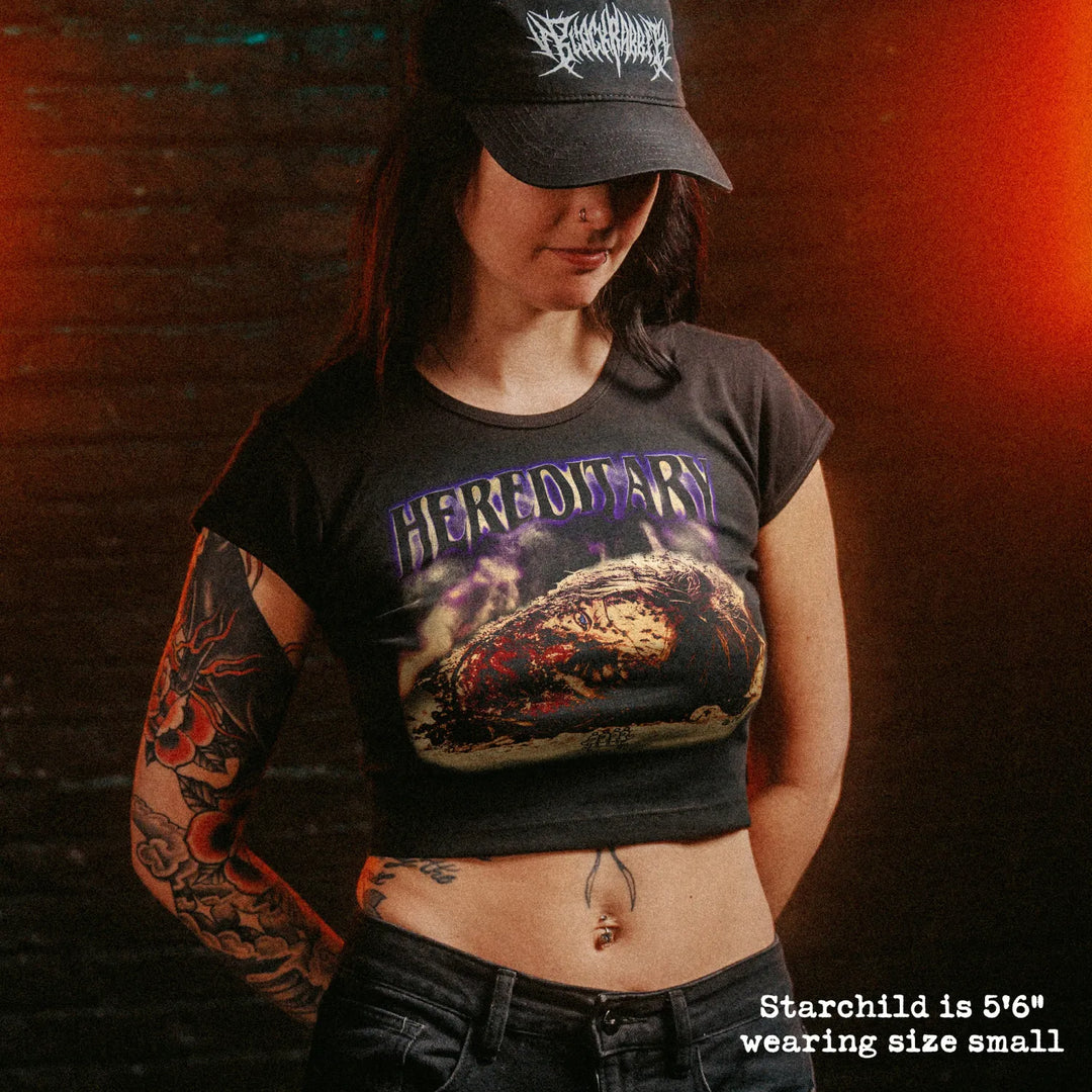 Female model wearing cropped baby tee with hereditary head graphic

