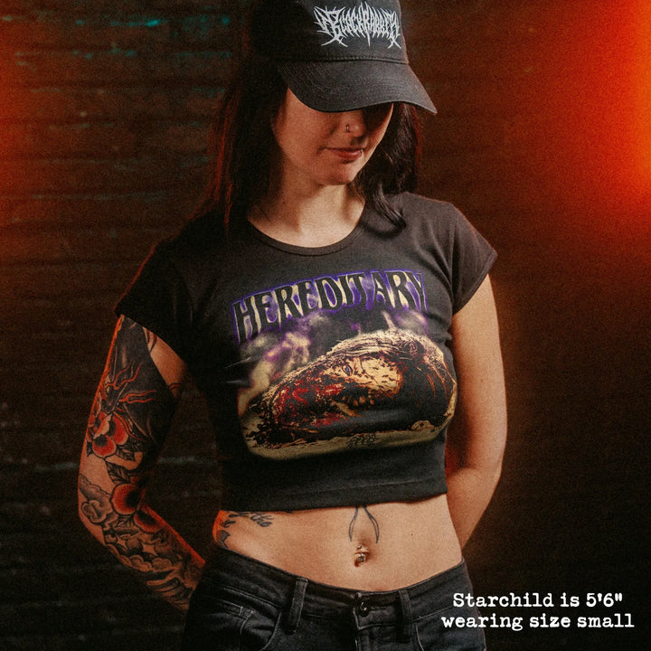 Female model wearing cropped baby tee with hereditary head graphic
