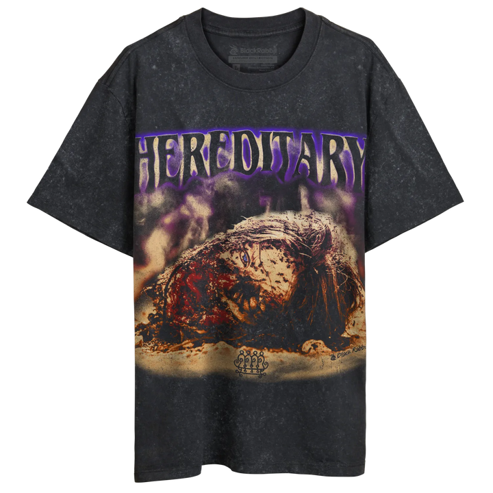 A dark gray, short-sleeved t-shirt with a distressed texture and a graphic print featuring purple ’HEREDITARY’ text and a gruesome, decaying head.