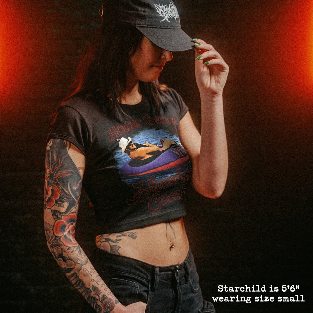 Female model wearing cropped baby tee with hotter than a hoochie coochie graphic
