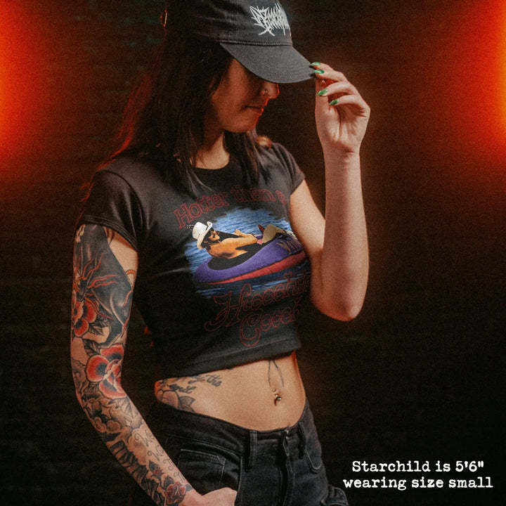 Female model wearing cropped baby tee with hotter than a hoochie coochie graphic
