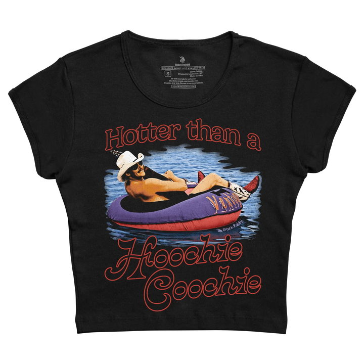 Black cropped t-shirt featuring a vibrant graphic of a man lounging in a purple and red inflatable tube with the text ’hotter than a hoochie coochie’ printed in bold orange lettering.