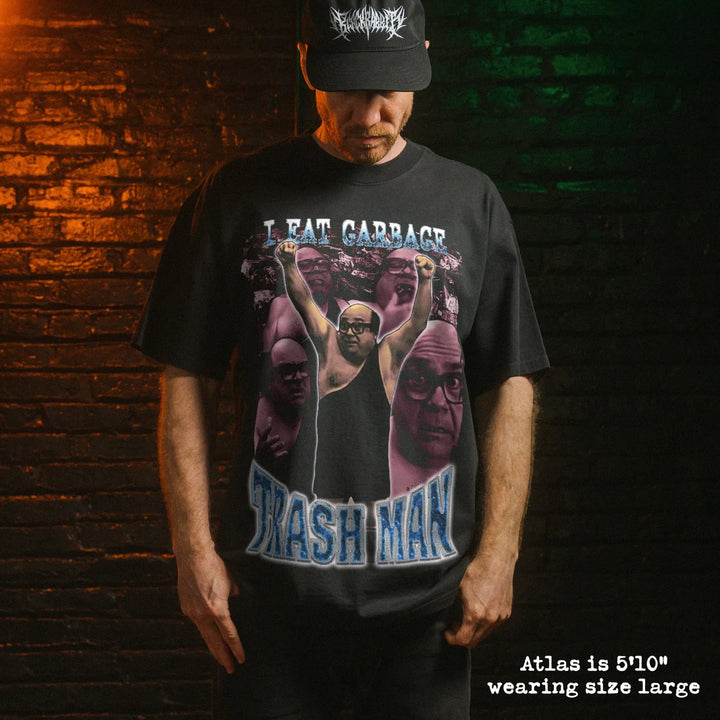 Black t-shirt featuring trash man wrestling graphic with text i eat garbage and trash man worn by man frank reynolds