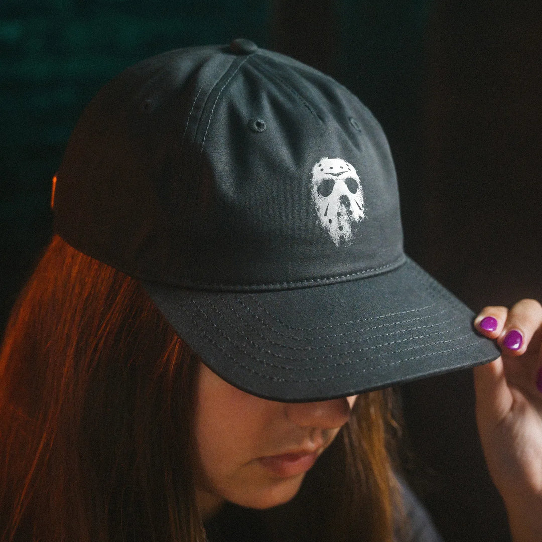 Female model wearing Black Rabbit's black unstructured Dad Hat featuring white distressed hockey mask graphic