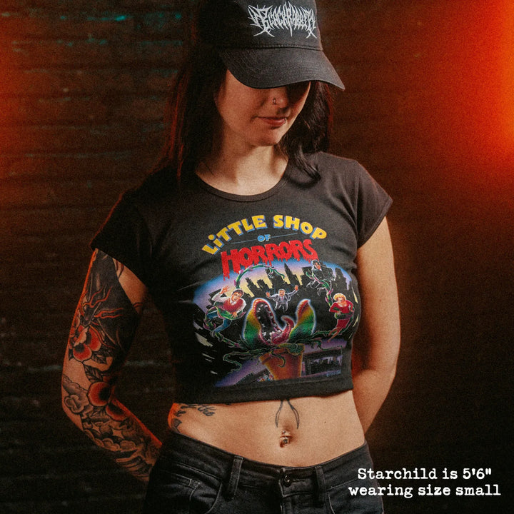 Female model wearing cropped baby tee with little shop of horrors graphic
