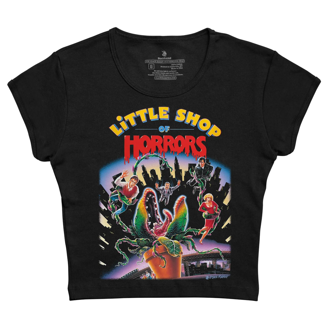 Black short-sleeved t-shirt featuring a vibrant, colorful graphic of the ’little shop of horrors’ movie poster with characters and the iconic plant. 