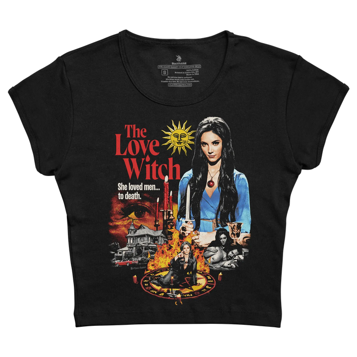 Black short-sleeved t-shirt featuring a vibrant graphic of ’the love witch’ movie poster with red and yellow text, an illustration of the main character in blue attire holding candles, surrounded by imagery including a house, flames, and occult symbols.