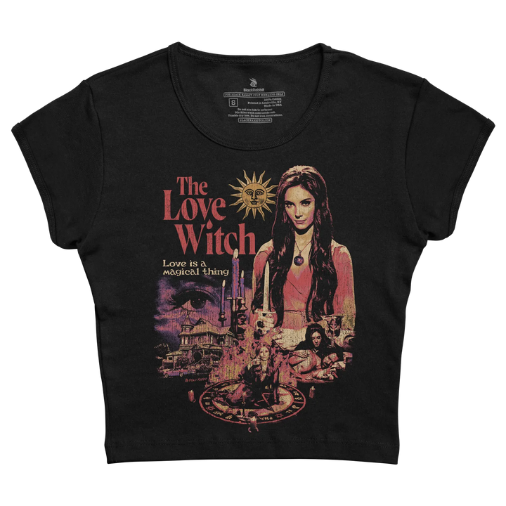 Black short-sleeved t-shirt featuring a vintage-style graphic of ’the love witch’ with pink and purple hues, depicting the main character alongside candles, an eye motif, and a witch’s circle.