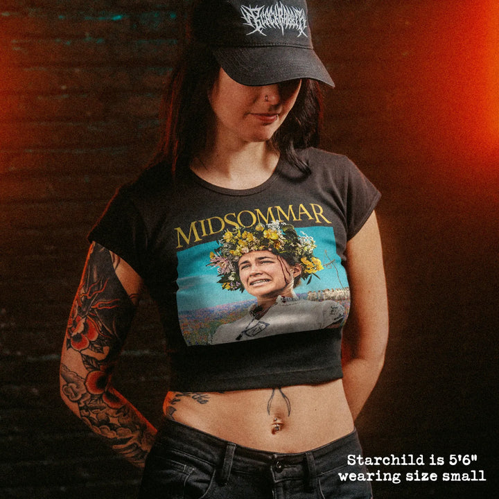 Female model wearing cropped baby tee with midsommar graphic
