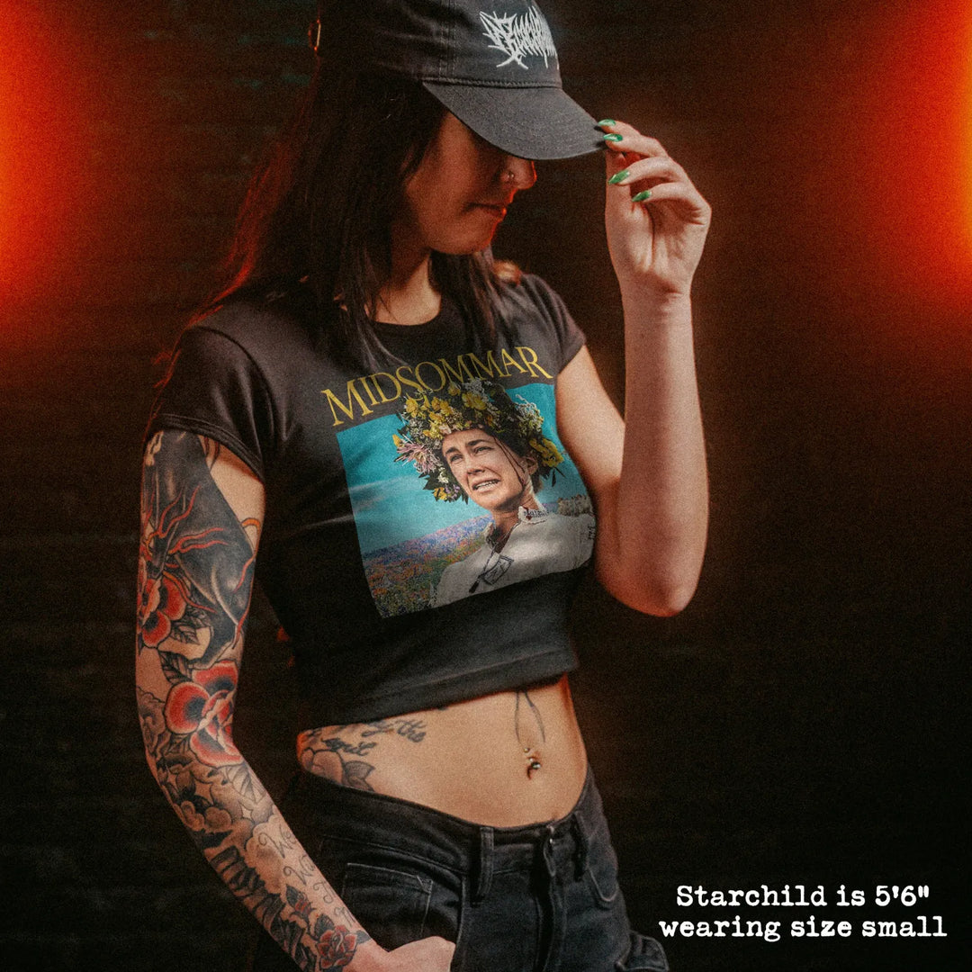 Female model wearing cropped baby tee with midsommar graphic
