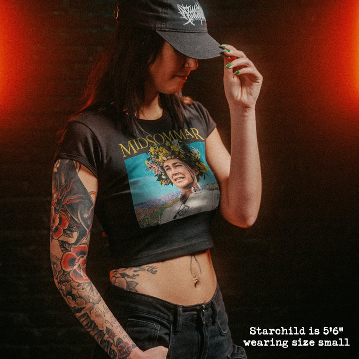 Female model wearing cropped baby tee with midsommar graphic
