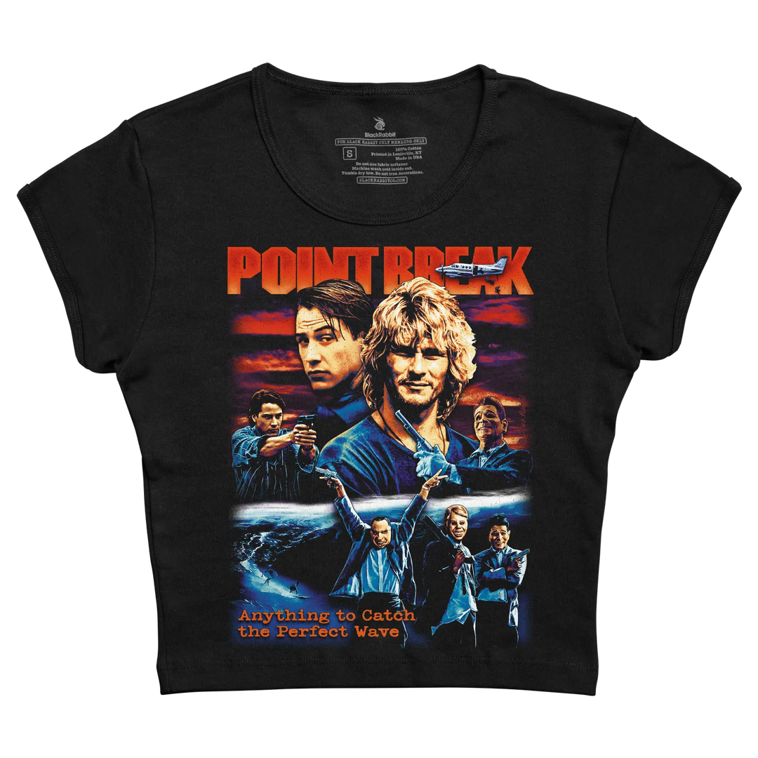 Black short-sleeved t-shirt featuring a vibrant graphic of the movie ’point break’ with orange and blue tones, depicting characters against a sunset ocean backdrop.