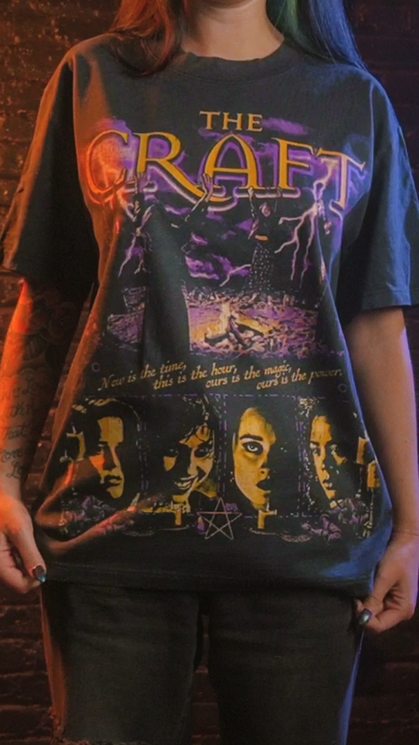 Black graphic t-shirt with a purple and gold ’The Craft’ design. 