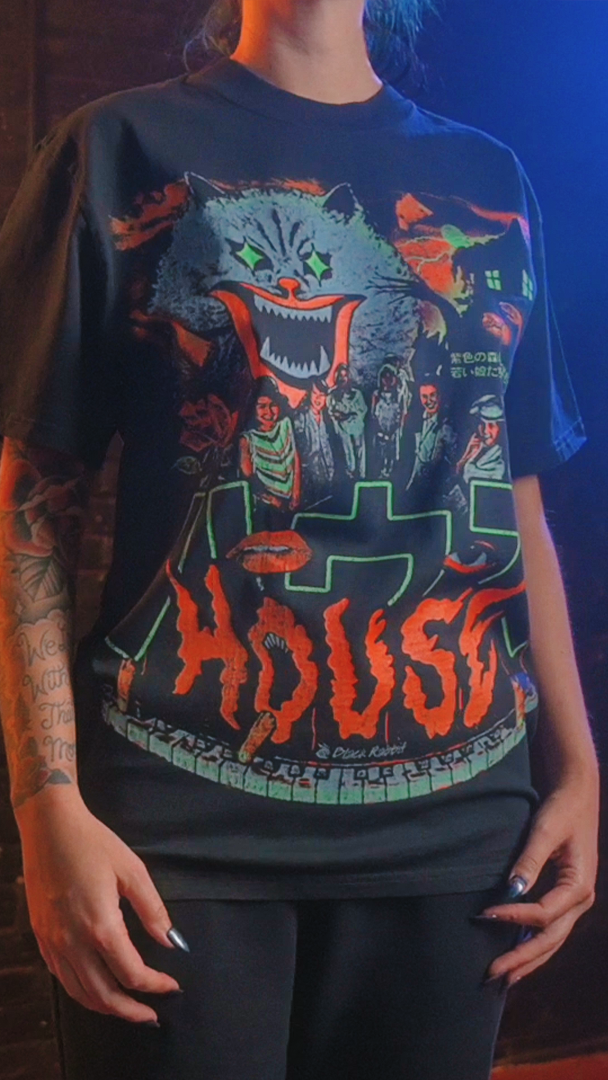T shirt featuring a graphic print of a monster and a house. 
