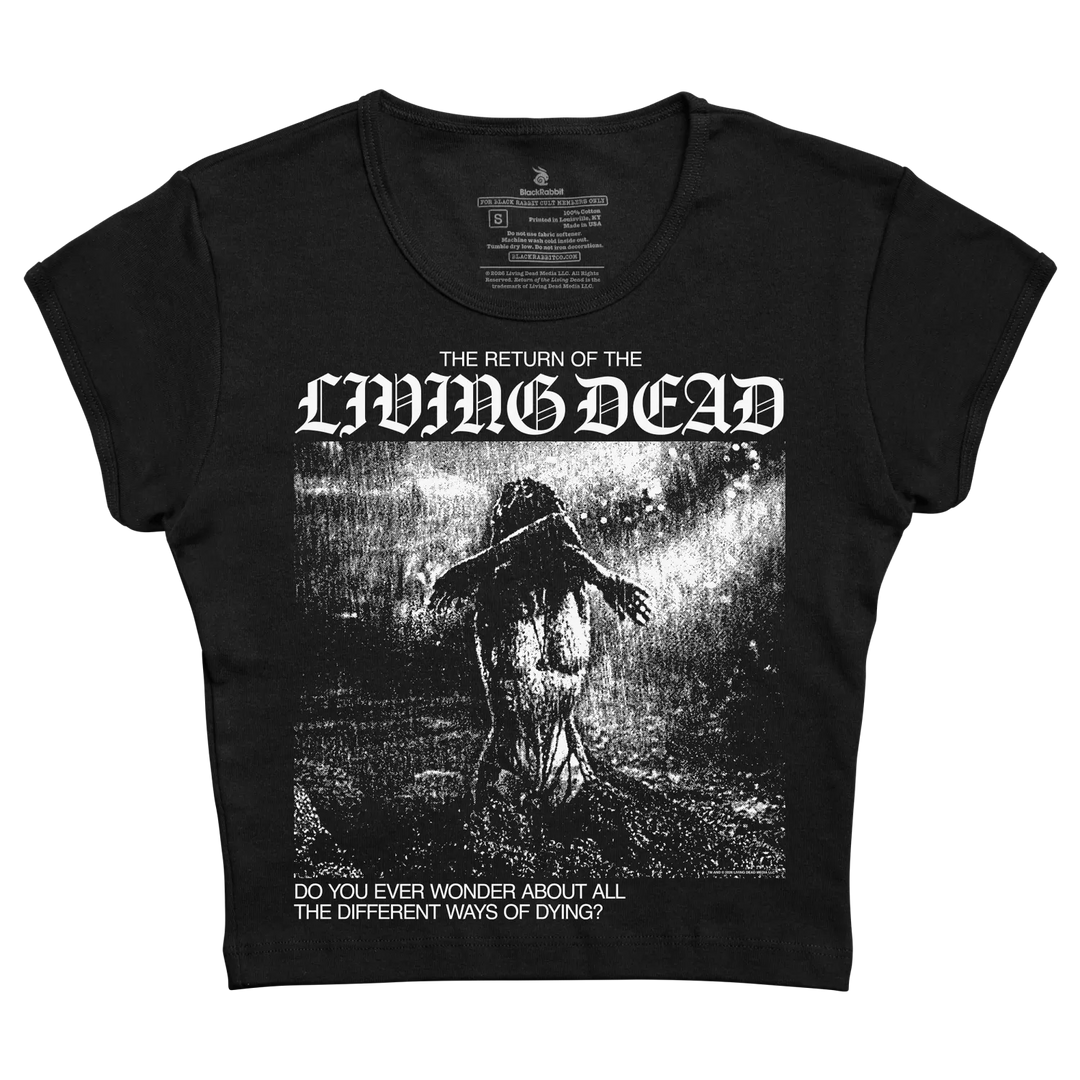 A black short-sleeve scoop-neck cropped women's baby tee featuring a high-contrast black and white graphic print of 'The Return of the Living Dead' with a zombie illustration and gothic text.