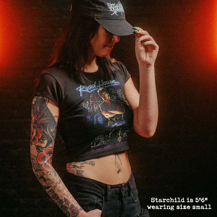 Female model wearing cropped baby tee with road house graphic
