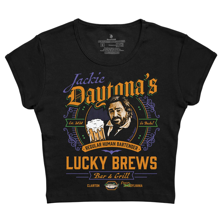 Black short-sleeved t-shirt featuring a colorful graphic of jackie daytona with text reading ’lucky brews bar & grill’ and ’regular human bartender.’