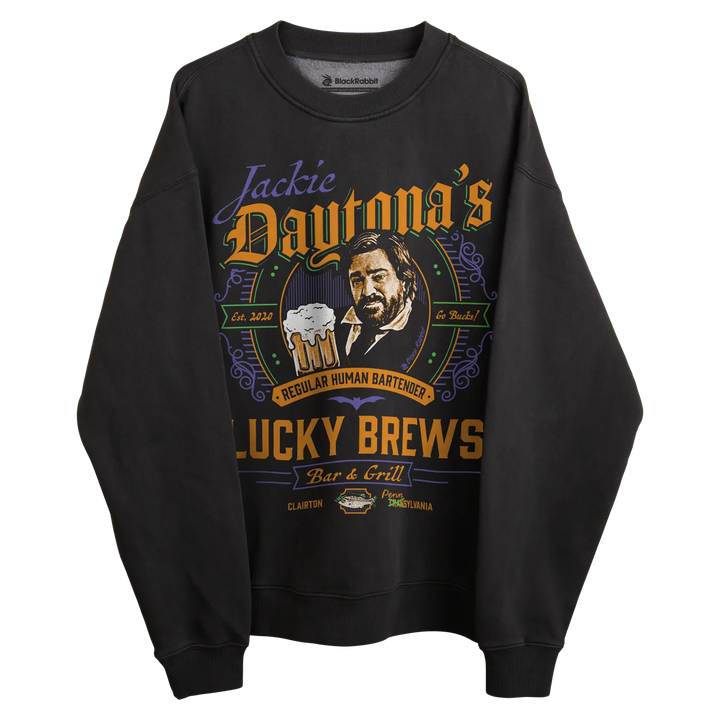 Black long-sleeved sweatshirt with ’jackie daytona’s lucky brews’ graphic design featuring a man holding beer, dark blue and orange accents.