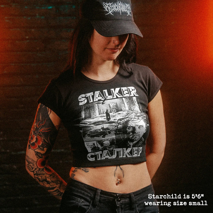 Female model wearing cropped baby tee with stalker graphic
