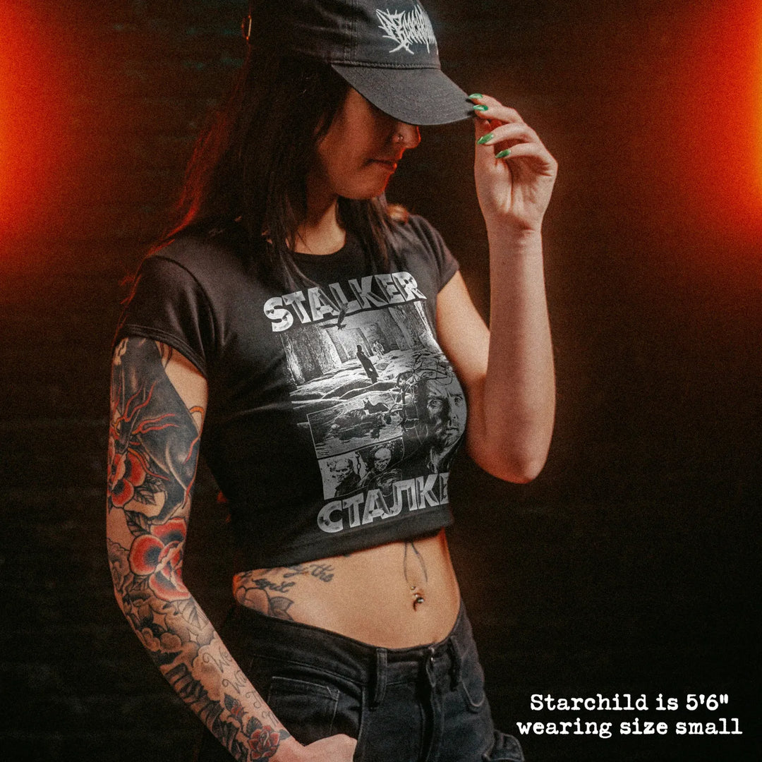 Female model wearing cropped baby tee with stalker graphic
