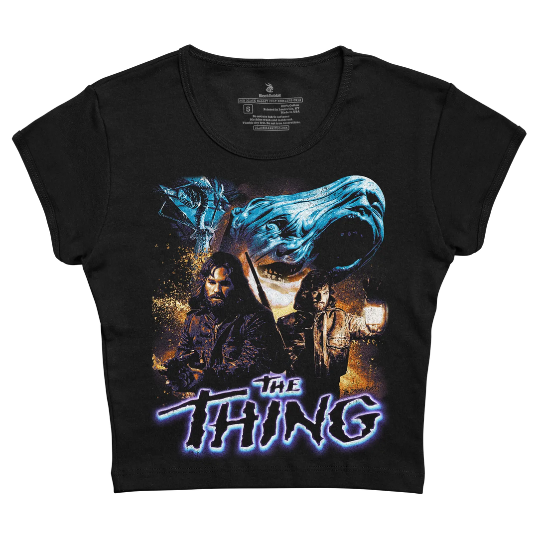 Black short-sleeved t-shirt featuring a graphic print of the movie ’the thing’ with blue and orange hues, depicting characters and a monstrous face.